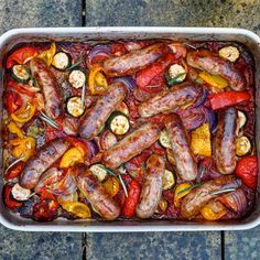 sausages and peppers in a casserole dish ready to be cooked on the grill