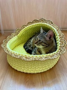 a cat laying in a yellow basket on the floor