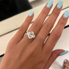 a woman's hand with blue fingernails and a ring on her finger, in front of a mirror