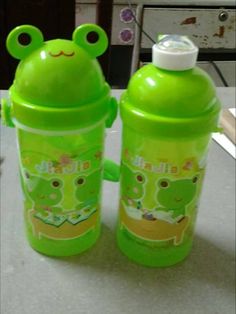 two children's sippy cups with frog faces on them, one green and the other yellow