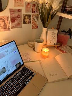 an open laptop computer sitting on top of a desk next to a vase with flowers