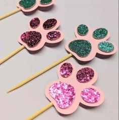 four pink and green paw prints on toothpicks with glitter hearts in the middle