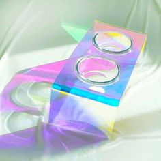 two rings sitting on top of a purple and blue box with clear plastic wrap around it