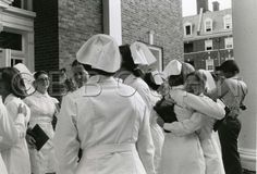 black and white photograph of nurses walking down the street with their arms around each other