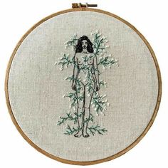 the embroidery on this hoop has an image of a woman with flowers in her hair