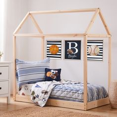 a child's bed with a wooden frame and baseball themed decor on the wall