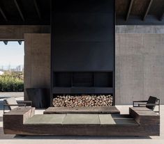 an outdoor fire place with two chairs and a couch in the foreground, next to a fireplace