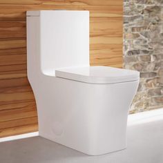 a white toilet sitting next to a brick wall in a room with wood paneling