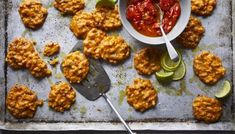 an overhead view of some food on a baking sheet with a spoon and fork next to it