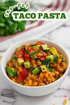 a white bowl filled with taco pasta and topped with tomatoes, avocado and cilantro