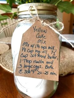 a jar filled with yellow cake mix sitting on top of a table next to a potted plant