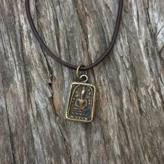 A framed Buddhist  amulet on a adjustable brown leather cord that expands to 30 inches long  Made to order , please allow 1-2 days Approximate pendant dimensions; H 1.25 X W 0.5 inches Adjustable Amulet Style Jewelry, Nickel Free Medallion Amulet Jewelry, Small Symbolic Handmade Jewelry, Symbolic Adjustable Rectangular Jewelry, Adjustable Coin Pendant Jewelry, Amulet Style Coin Pendant Jewelry, Adjustable Medallion Jewelry For Meditation, Handmade Rectangular Necklaces For Meditation, Spiritual Rectangular Jewelry For Good Luck