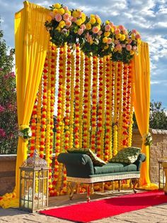 an outdoor wedding setup with yellow drapes and flowers on the wall, green couch