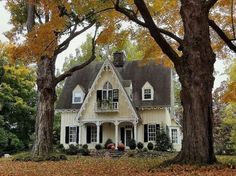 a white house surrounded by trees and leaves