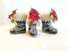 three pairs of boots decorated with poinsettis and bows, on a white background