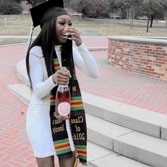 a woman wearing a graduation cap and gown is drinking from a bottle while standing on steps