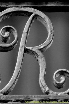 black and white photograph of the letter r on an old iron fence with swirls