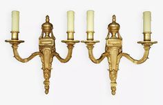 a set of four brass wall lights with candles on each arm and one candle in the middle