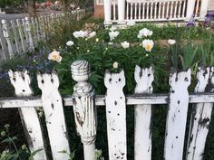 an old white picket fence with flowers growing on it