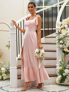 a woman in a pink dress standing next to a stair case with flowers on it