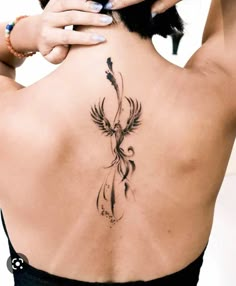 the back of a woman's neck with a bird tattoo on it