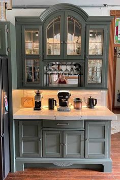 a kitchen with green cabinets and marble counter tops