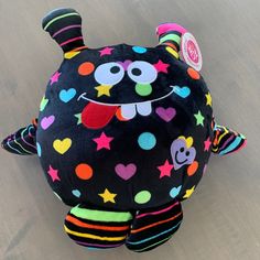 a black stuffed animal with multicolored stars and hearts on it's face