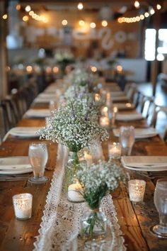 a long table is set with candles and vases filled with baby's breath flowers