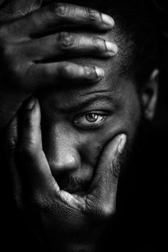 a black and white photo of a man holding his hands to his face with one hand