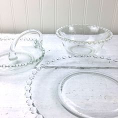 three clear glass dishes sitting on top of a white wooden table next to each other