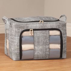 a grey and white storage bag sitting on top of a wooden floor