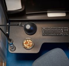 a computer desk with a bowl of food on it