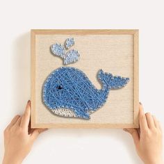 someone is holding up a blue whale string art