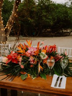 a wooden table topped with flowers and greenery