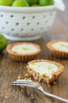 a small bowl filled with limes next to some crackers on a wooden table