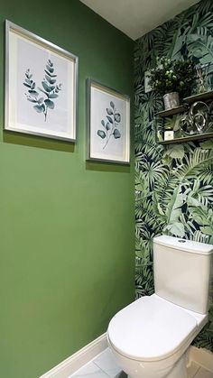 a white toilet sitting in a bathroom next to a green wall with pictures on it