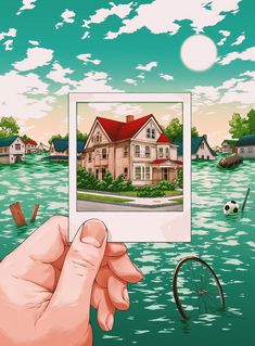 a hand holding up an image of a house in the water with a bicycle nearby