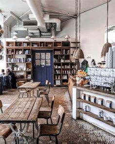 an empty restaurant with tables and chairs in front of the bookshelves filled with food