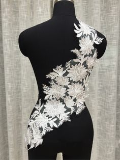 a mannequin with white flowers on it's back and side, in front of a curtain