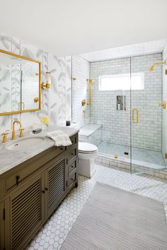 a bathroom with marble counter tops and gold accents on the walls, along with a walk in shower