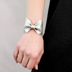 "Silver Bow Tie Vegan Leather Wide Cuff Bracelet by ForgottenCotton Get Festive. Our silver bow tie cuff is perfect 'oh so adorable' accessory. Dressed up or down, it is versatile, cute, and sure to get tons of compliments. In always stylish metallic silver, it will add a pop to any outfit. Why we love it: Our cuffs are made to be versatile. You can wear our cuffs on either your wrist or your scarf (or both!) We chose high quality vegan leather that has the look and feel of leather without the g Chic Adjustable Leather Bracelet For Parties, Adjustable Wrist Strap Wristlet For Party, Adjustable Wristlet With Wrist Strap For Party, Adjustable Elegant Leather Bracelet For Party, Modern Adjustable Cuff Bracelet For Party, Modern Adjustable Cuff Bracelet For Parties, Adjustable Modern Cuff Bracelet For Party, Elegant Leather Bangle Bracelet For Party, Elegant Formal Leather Cuff Bracelet