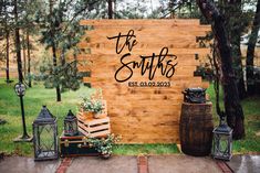 a wooden sign sitting on top of a lush green field next to trees and lanterns