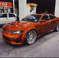 an orange car parked in front of a gas station