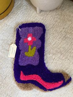 a purple sock with a flower on it sitting on the floor next to a potted plant