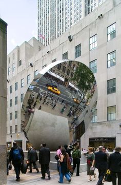 people are walking around in front of a large mirror on the side of a building