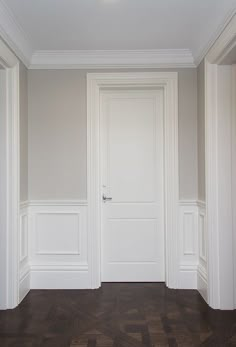 an empty room with wooden floors and white walls, the door is open to reveal another room