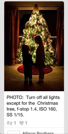 two children standing in front of a christmas tree