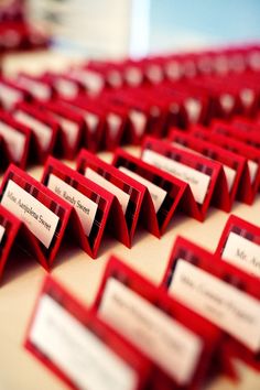 there are many red business cards that are on the table with name tags attached to them