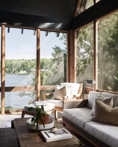 a living room filled with furniture and large windows overlooking the water in front of it