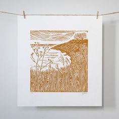 an orange and white print hangs on a clothes line next to a string that has some type of artwork hanging from it